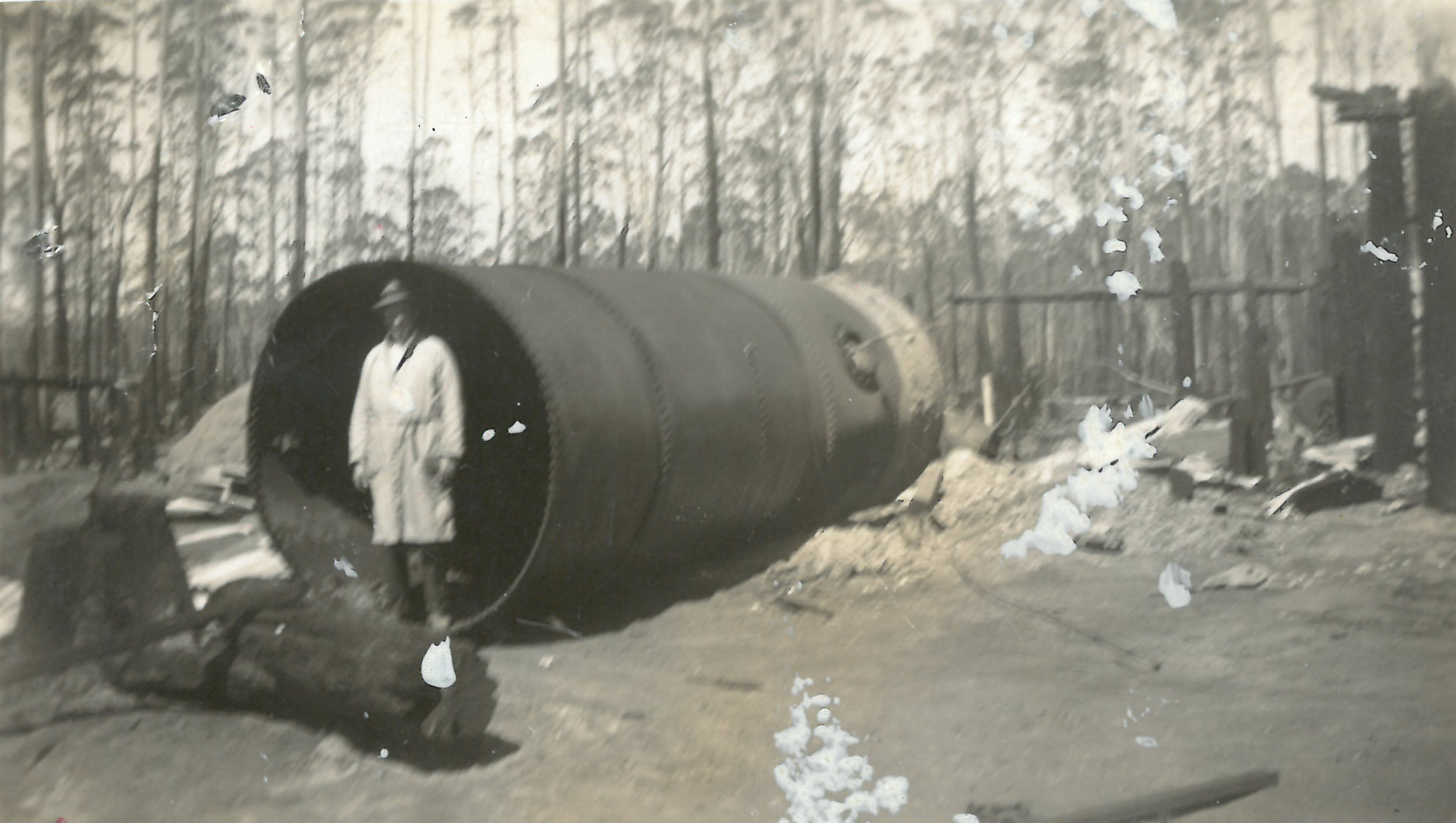 black and white photo of tank with burned landscape around and man in front