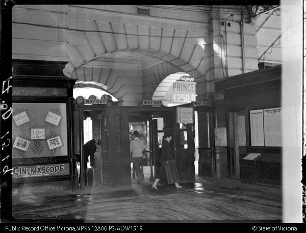 black and white photo inside Flinders Street Station with a pinboard in the background