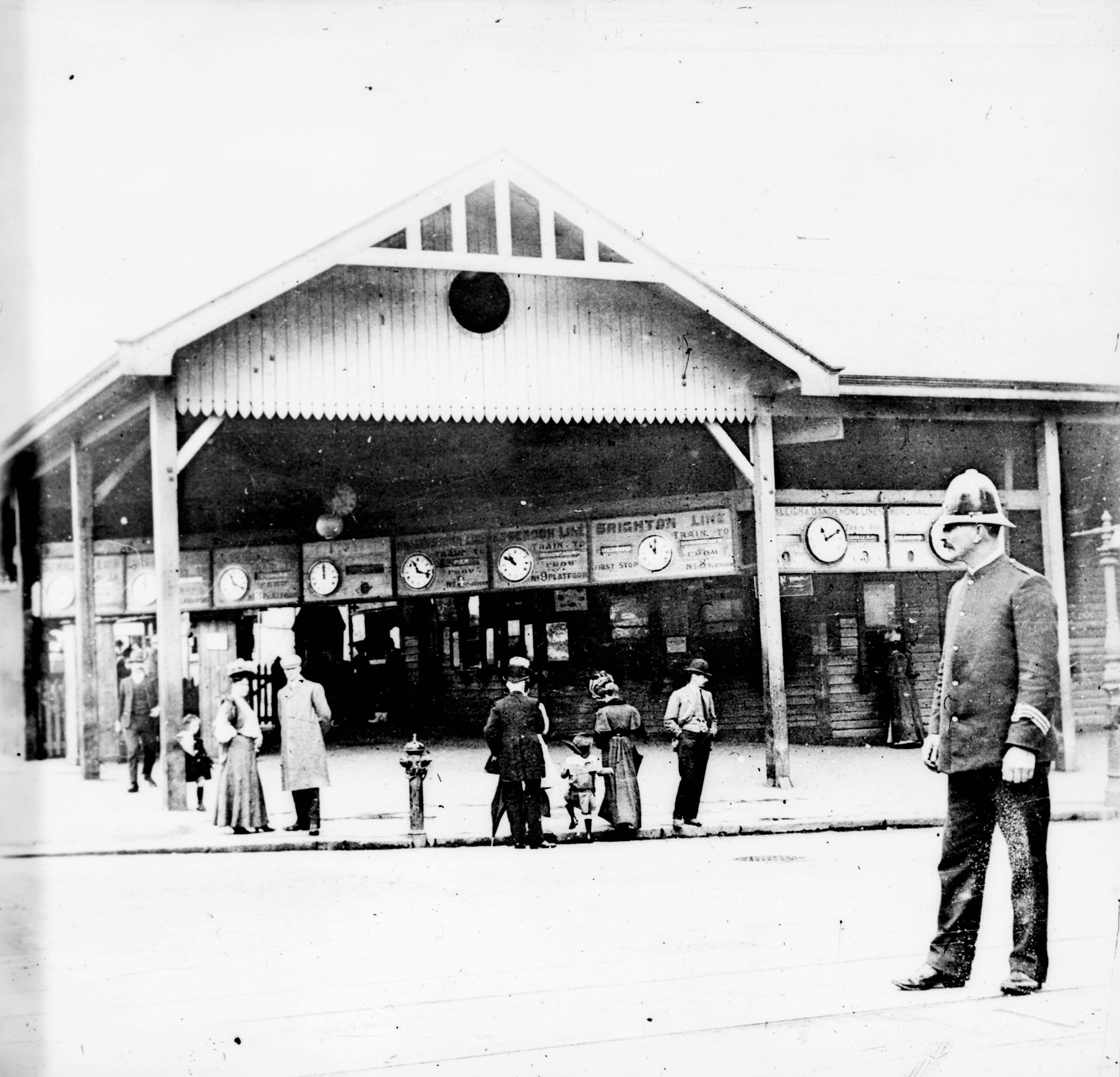 Black and white image of a police officer standing outside flinders street station