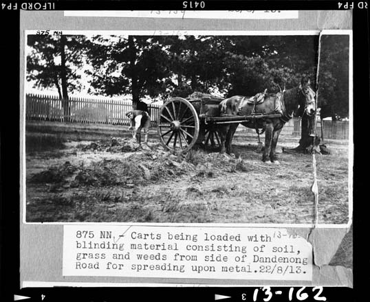 black and white photo of a horse and cart being loaded with construction materials