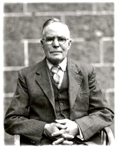 black and white photo of old man wearing glasses, facing the camera